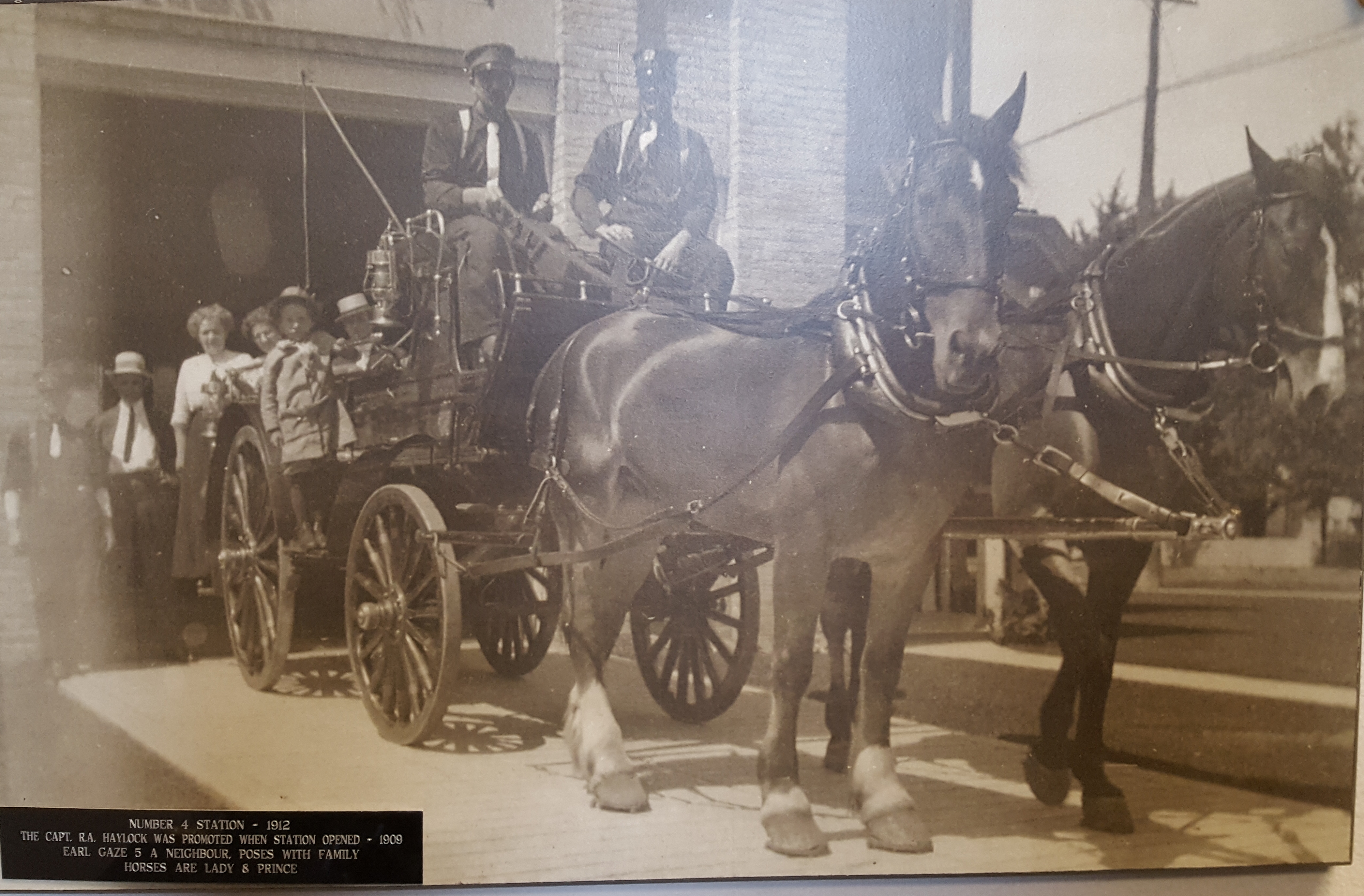 Crew pose with horses and apparatus in front of station with neighours.