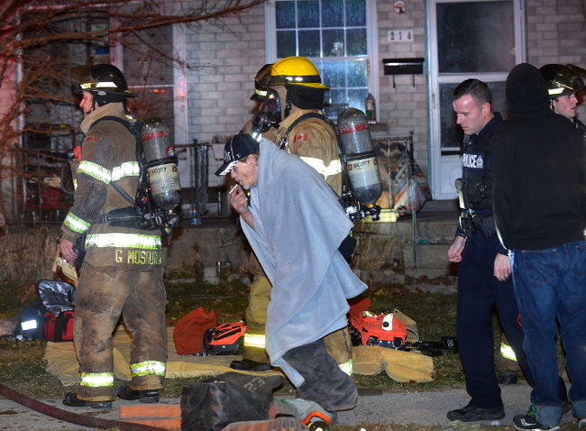 Police officer and two fire fighters around a civilian wrapped in a blanket