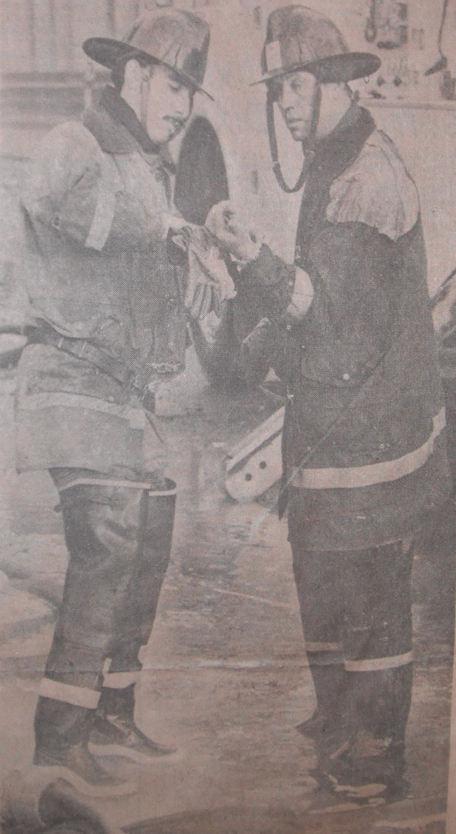 London Firemen Morley Hanes, left, and Don Varey stop for a moment to attend to an injury to Mr. Varey's hand. (photo by Rick Eglington of The London Free Press)