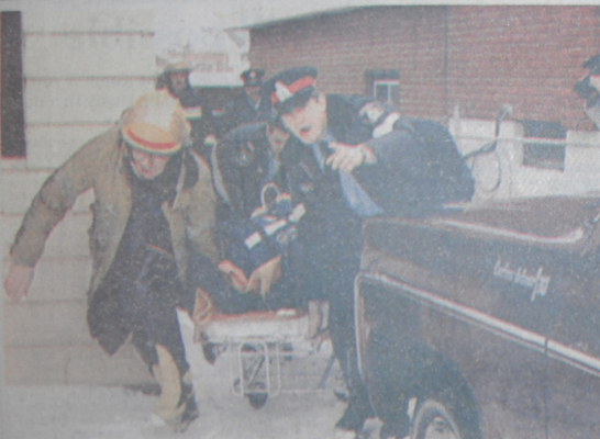 EMS, Police and fire fighters moving stretchered victim to ambulance