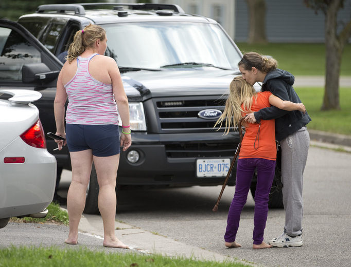  An unidentified woman walks out of a house with a police officer on Fitzroy Place where a two-year-old was pulled from a backyard pool without vital signs shortly before 4 p.m. Friday. The child died, police later said. (CRAIG GLOVER The London Free Press / QMI AGENCY)