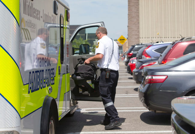A paramedic carries a child’s car seat into an ambulance after the car it was in crashed into an emergency exit door Tuesday at Costco in north London. (CRAIG GLOVER, The London Free Press)