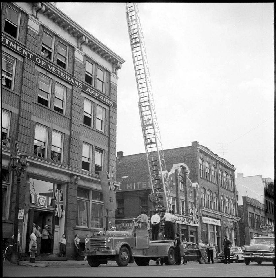 The London Fire Department is shown here trying out an aerial ladder on a new fire truck, being demonstrated by a Quebec company in various Ontario cities. The demonstration occured on King St, between Clarence & Richmond, across the road from the central Fire Hall. Deputy Fire Chief Tom Hepburn was one of those who tested out the new ladder. Visible on the left is the Garvey Building (home to the Department of Veteran Affairs & later Goodlife Fitness), now home to Innovation Works - at 201 King St.