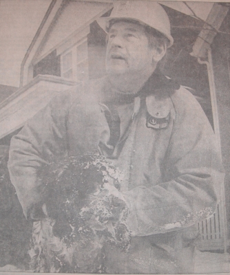 Firefighter holding black spaniel rescued from a house fire.