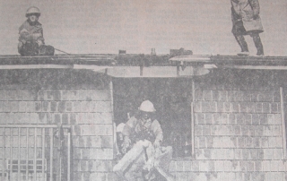 Firemen drop soggy chunks of insulation from the third-storey