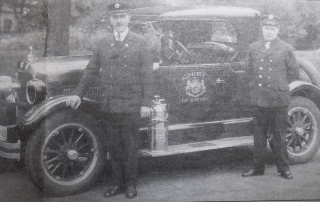 Fire Chief Jenner and Firefighter Hanley posing with Chief's car