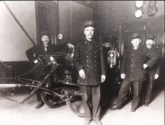Historic black-and-white photo of London Fire Department firefighters standing beside a fire service sleigh inside Station 3 on Bruce Street in London, Ontario, c. 1919