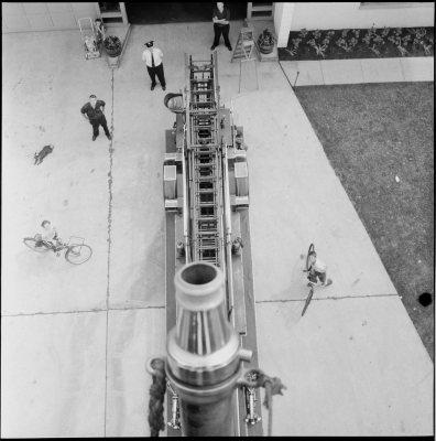 The camera perspective is from the elevated tip of Truck 2 looking down on children and fire fire fighters looking up.