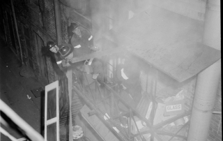 Four fire fighters battling smoke on a second floor fire escape
