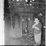 Fire fighters and onwer examine the charred remains