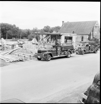 Two Firetrucks from Byron parked in front of partially constructed new firehall.