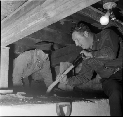 Two fire fighters digging out basement of fire hall