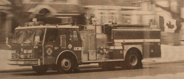 Engine 4 driving down the road with a Canadian flag on display on the back of the truck.