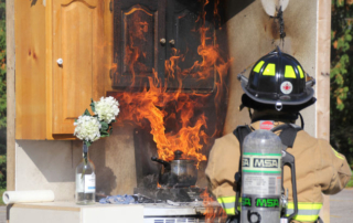 Fire fighter standing in front of stove that is on fire