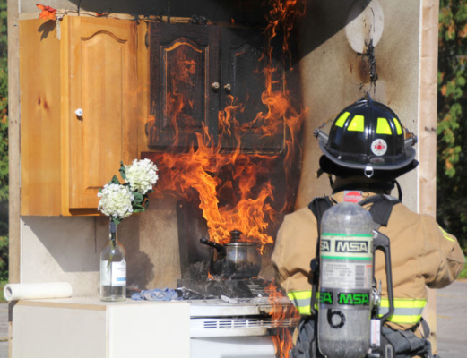 Fire fighter standing in front of stove that is on fire