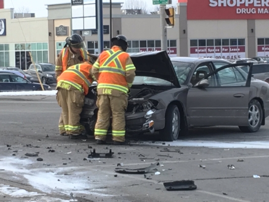 Two fire fighters looking at engine of vehicle involved in crash.