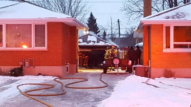Hose stretches up a driveway to an extinguished garage fire