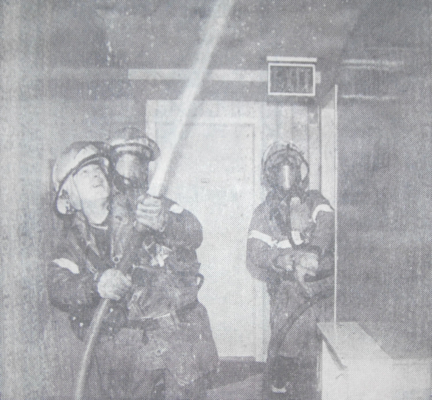 Fire fighters spraying water during an interior fire overhauling operation.