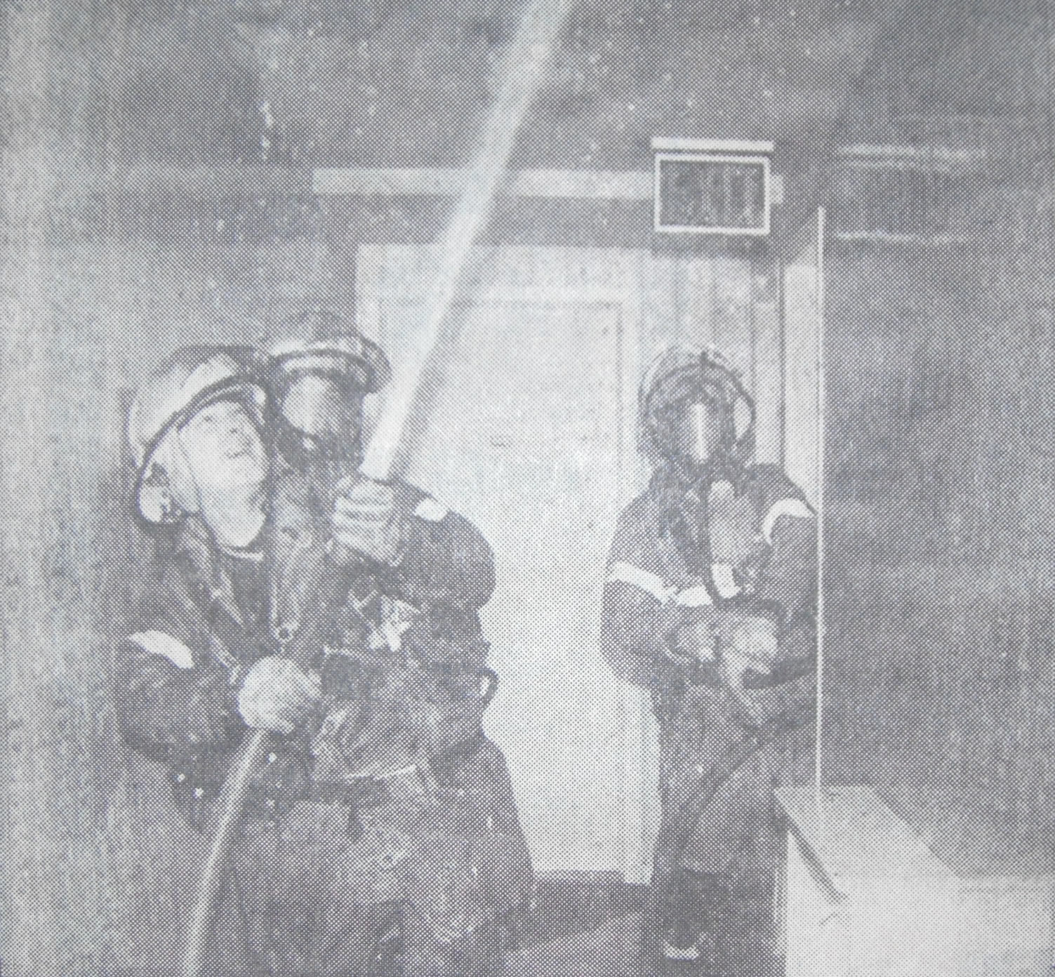 Fire fighters spraying water during an interior fire overhauling operation.