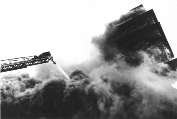 Firefighter on large ladder spraying water into large fire