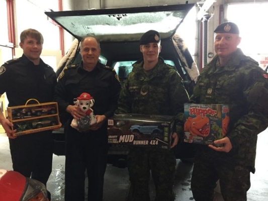 Firefighters and military personnel loading toys into vehicle
