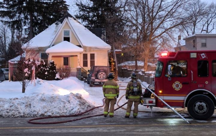 Fire fighters standing outside house that was on fire previously