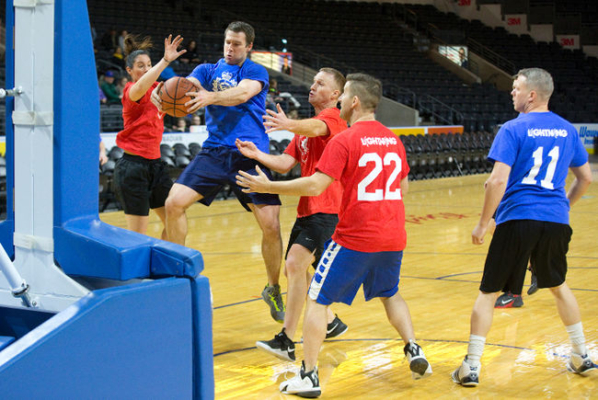 Three firefighters prevent a police officer from scoring in the basketball game