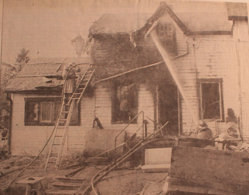 Firefighters on the roof and front yard spraying water on burned home.