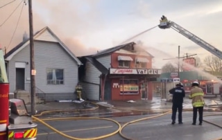 Large fire truck pouring water on burning building