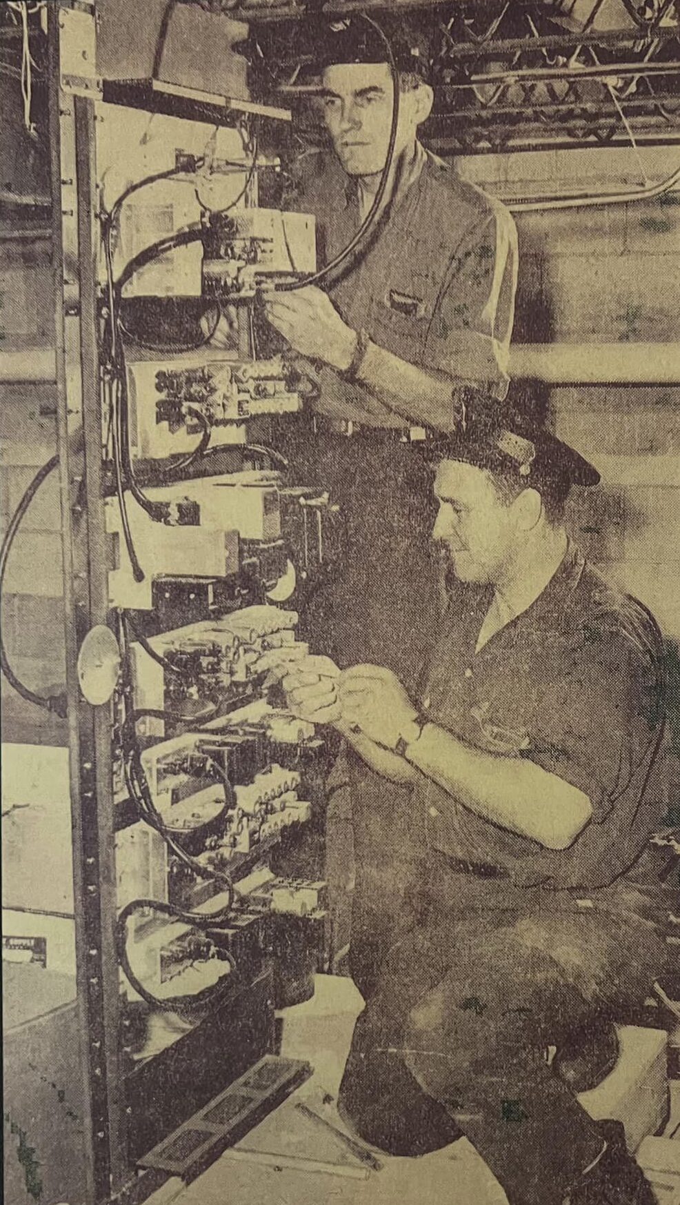 Murray Ragin, top and Joseph Nahoneczny, two of the fire department's electricians, work on the radio panel in the attic of Central Fire Hall. (Source: Jim Fitzgerald)