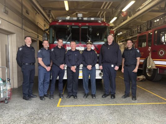 Fire fighters posing in front of a fire truck