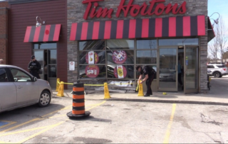 A London Police officer put caution tape around cones blocking off the sidewalk in front of the Tim Horton’s at 670 Wonderland Rd. N. in London, Ont. on March 24, 2024. (Brent Lale/CTV News London)