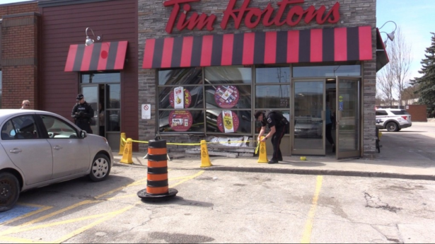 A London Police officer put caution tape around cones blocking off the sidewalk in front of the Tim Horton’s at 670 Wonderland Rd. N. in London, Ont. on March 24, 2024. (Brent Lale/CTV News London)