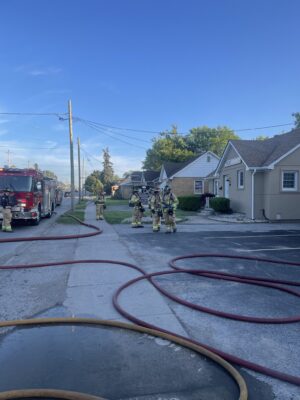 Crews post incident talking amongst hoses and equipment deployed at the scene.