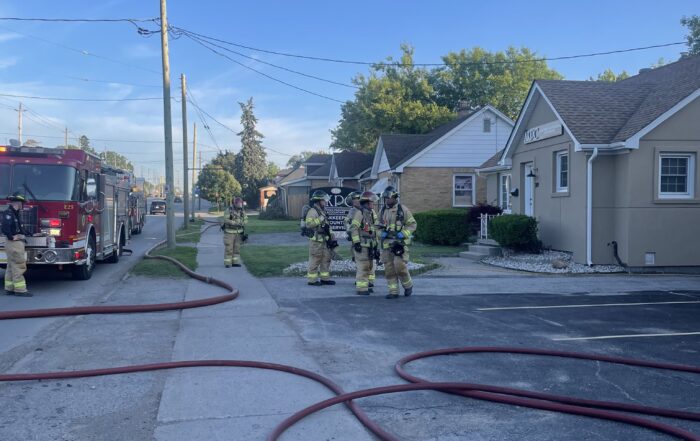 Crews post incident talking amongst hoses and equipment deployed at the scene.