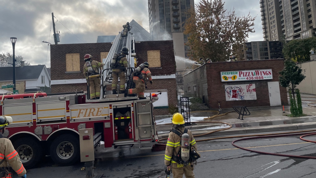 Large fire truck spary water from large ladder onto vacant two story building