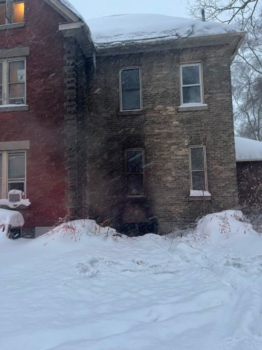 Soot stained brick work above the basement window of the home with the fire.