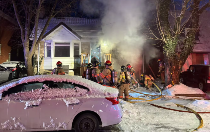 Steam released from a house fire. Fire fighters working in the front yard with hoses and equipent.