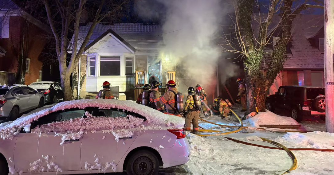 Steam released from a house fire. Fire fighters working in the front yard with hoses and equipent.