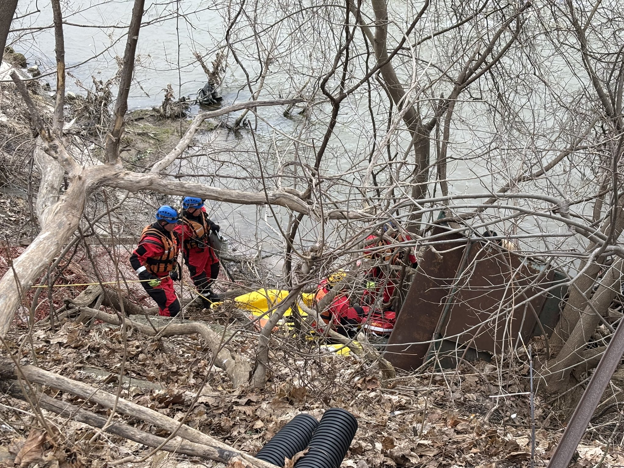LFD Water Ice Rescue Team members at the rivers' edge working through debris and trees to gain access to the patient in the waer