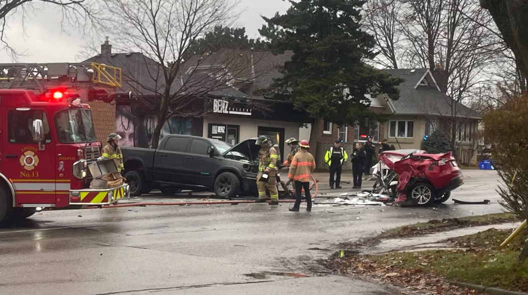Serious crash sends two people to hospital A black pickup truck and a severely damaged red car sit across Adelaide Street North after a major collision, with debris scattered over the roadway. Police officers and emergency responders stand near the wreckage while patrol vehicles block the road and emergency lights flash in the background.