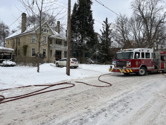 London Fire Department Engine No. 4, a red and white pumper truck, parked on a snowy residential street with fire hoses deployed while responding to a severed natural gas line emergency.