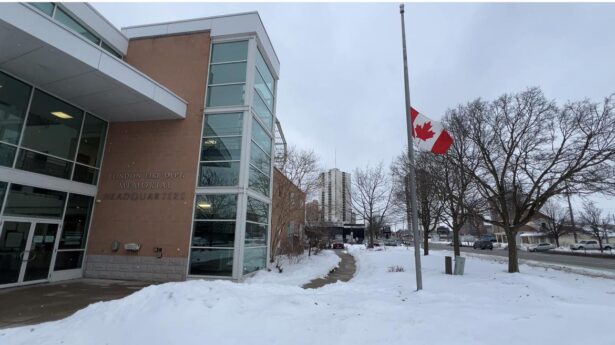 Canadian flag at half-mast outside London Fire Department Memorial Headquarters on a snowy winter day, recognizing those affected by the tragedy in Tumbler Ridge, British Columbia.