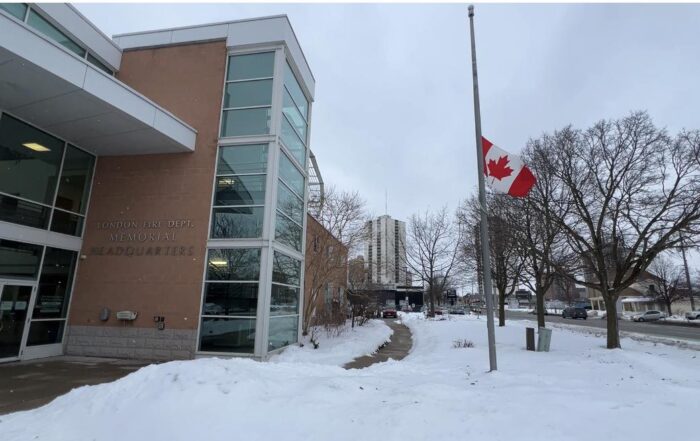 Canadian flag at half-mast outside London Fire Department Memorial Headquarters on a snowy winter day, recognizing those affected by the tragedy in Tumbler Ridge, British Columbia.
